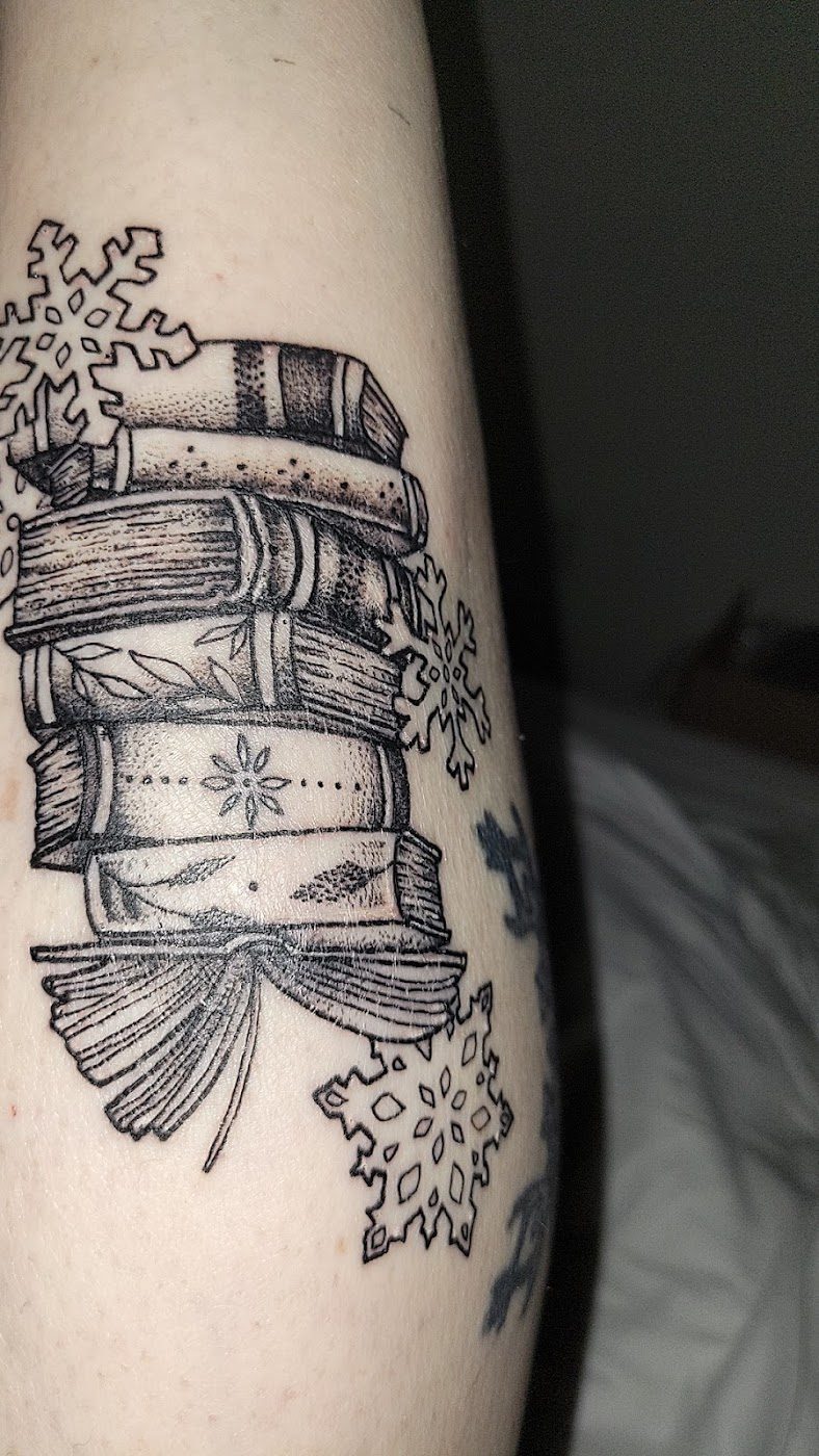 Black and grey stack of books forearm tattoo